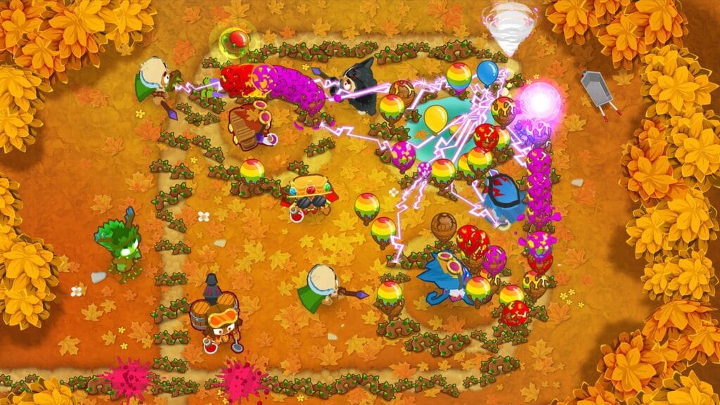 Bloons TD 6 gameplay showing a layered defense of monkey towers popping a wave of bloons